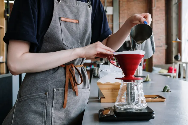 De barista zet een pour-over met een rode dripper