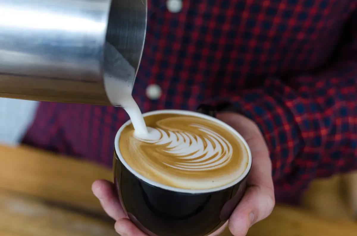 Een cappuccino met latte art in twee handen