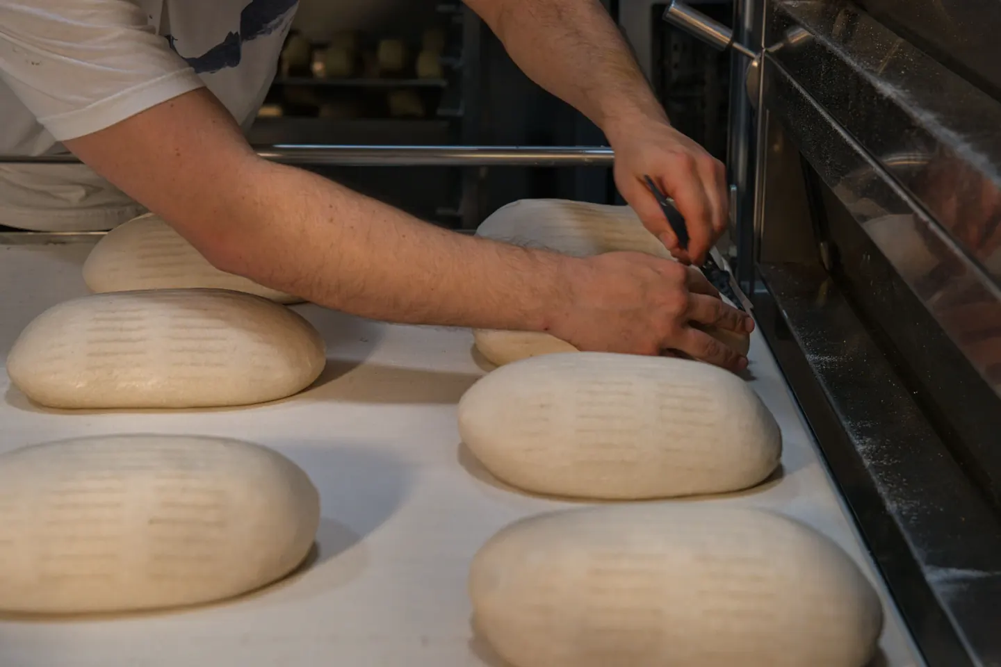 Bakker vormt broden op een met meel bestoven werkbank