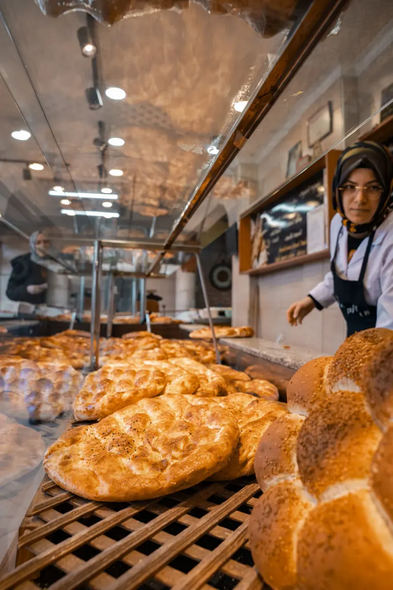 Bakker achter de toonbank van een warme bakkerij met broden in de vitrine