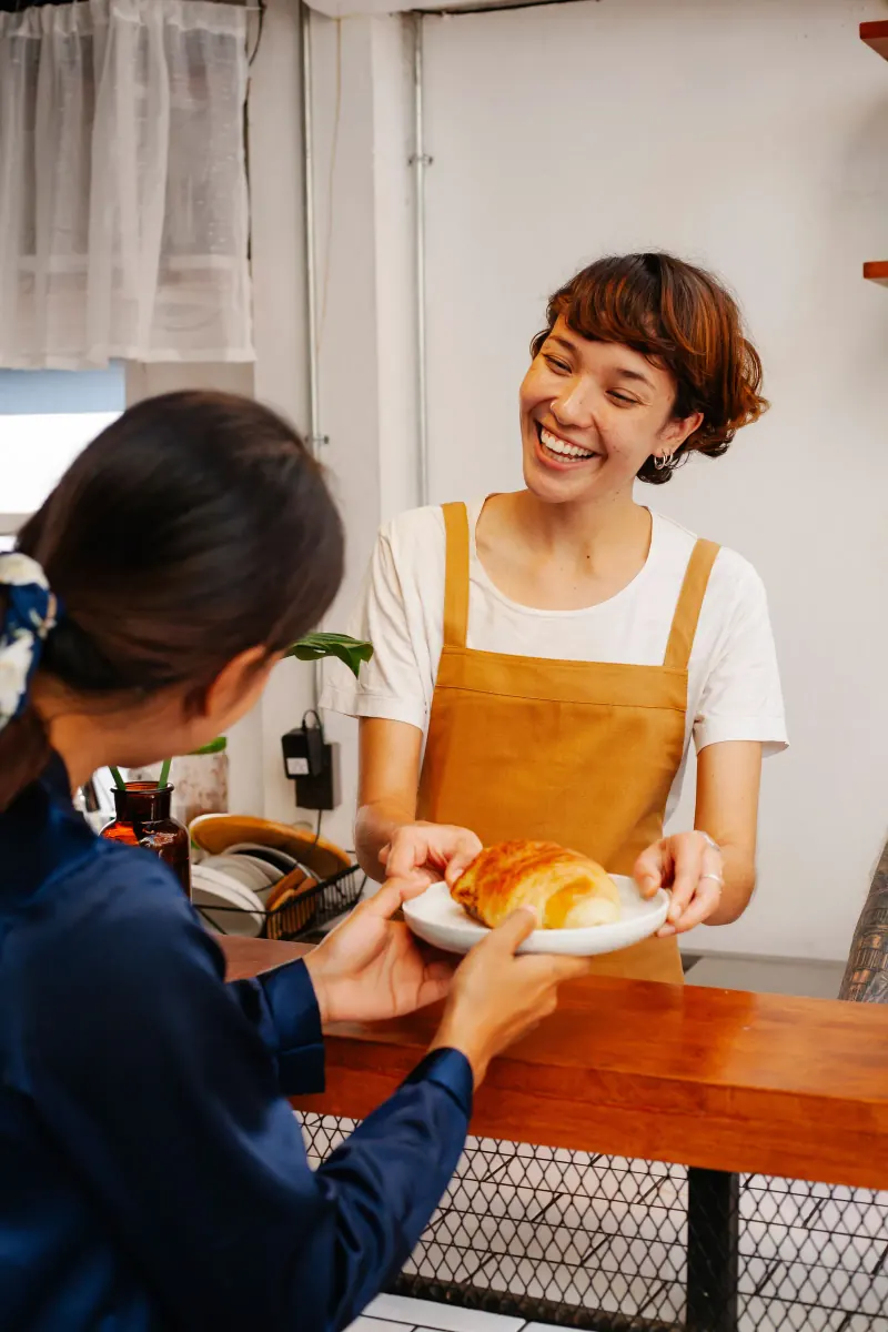 Verkoopster geeft een croissant aan een klant