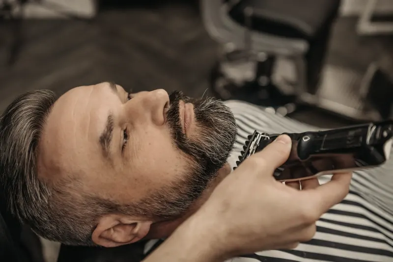 Een baard wordt bijgewerkt, het hoofd achterover in de stoel