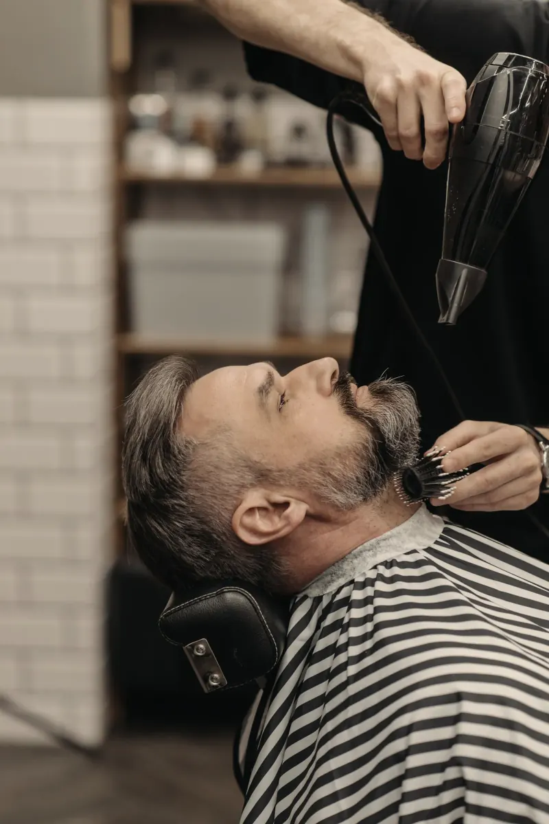Afgewerkte coupe en baard van opzij, in de stoel
