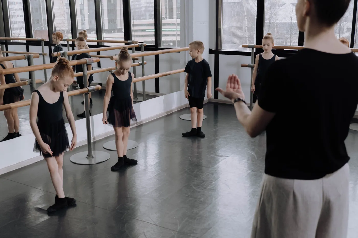 Kinderen aan de barre tijdens een balletles, de docent kijkt toe