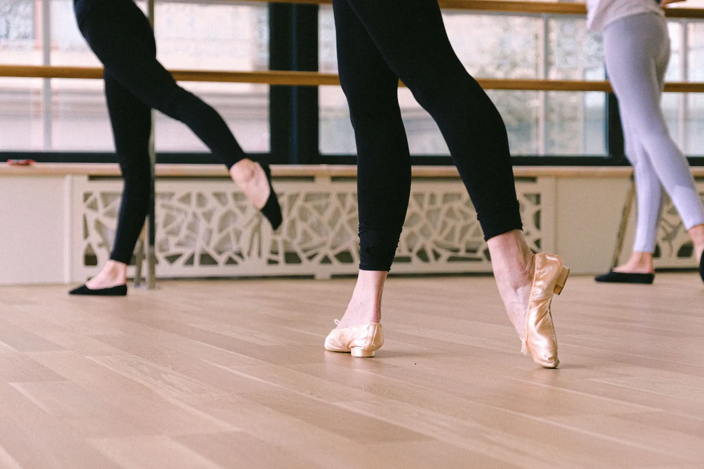 Balletschoenen en benen op de houten vloer, bij de barre