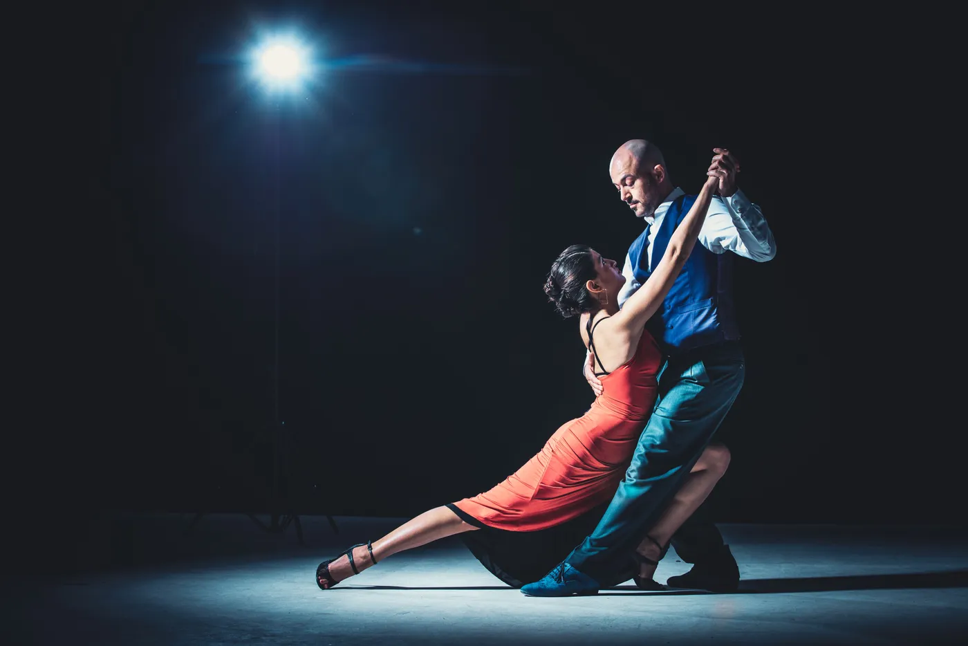 Een paar danst onder één spotlight op een donker podium