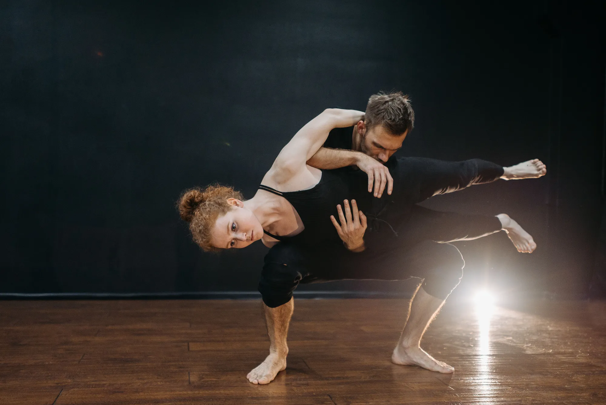 Twee dansers in een moderne lift, de man tilt de vrouw, tegen een zwarte achtergrond