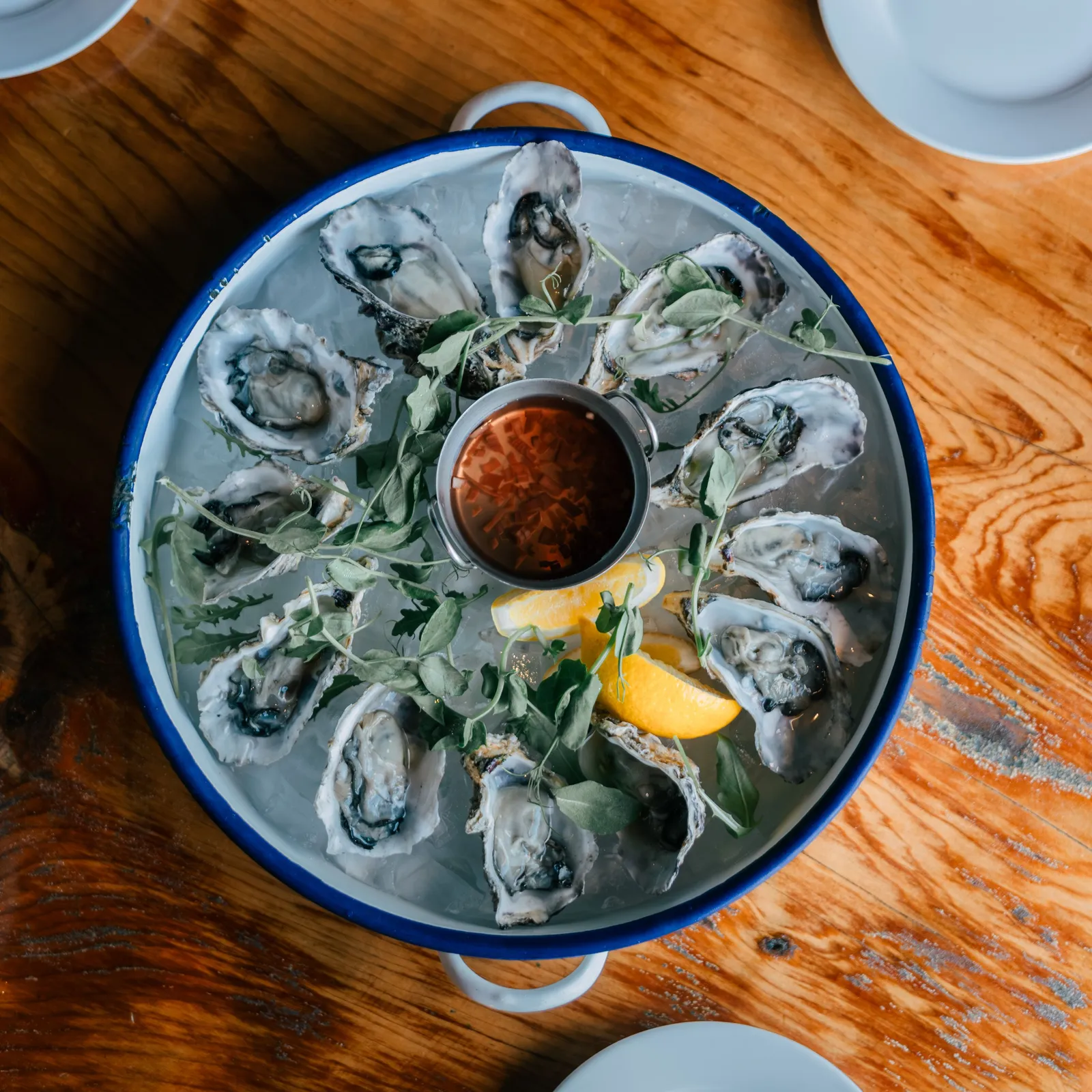 Verse oesters op ijs met citroen op een blauwe schaal