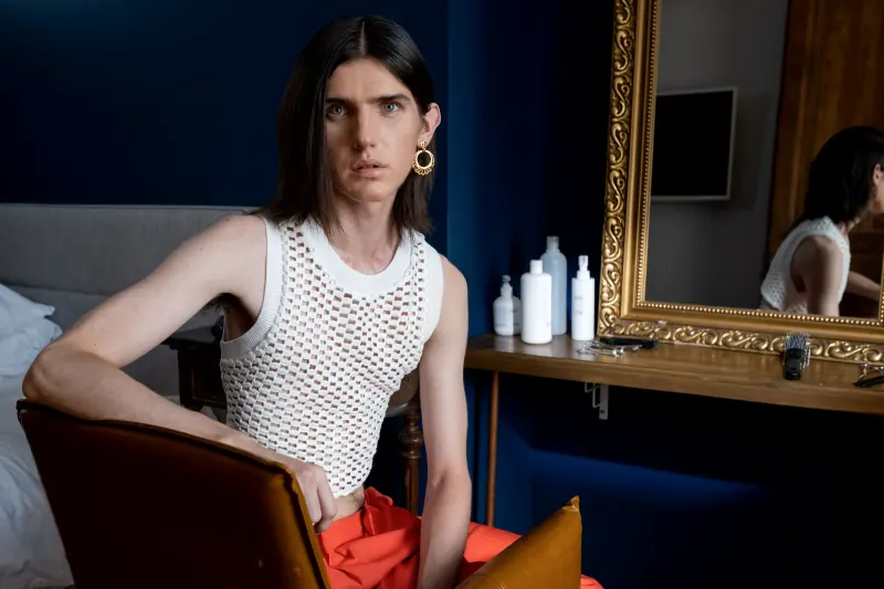 Klant met lang haar zit ontspannen in een stoel naast de spiegel