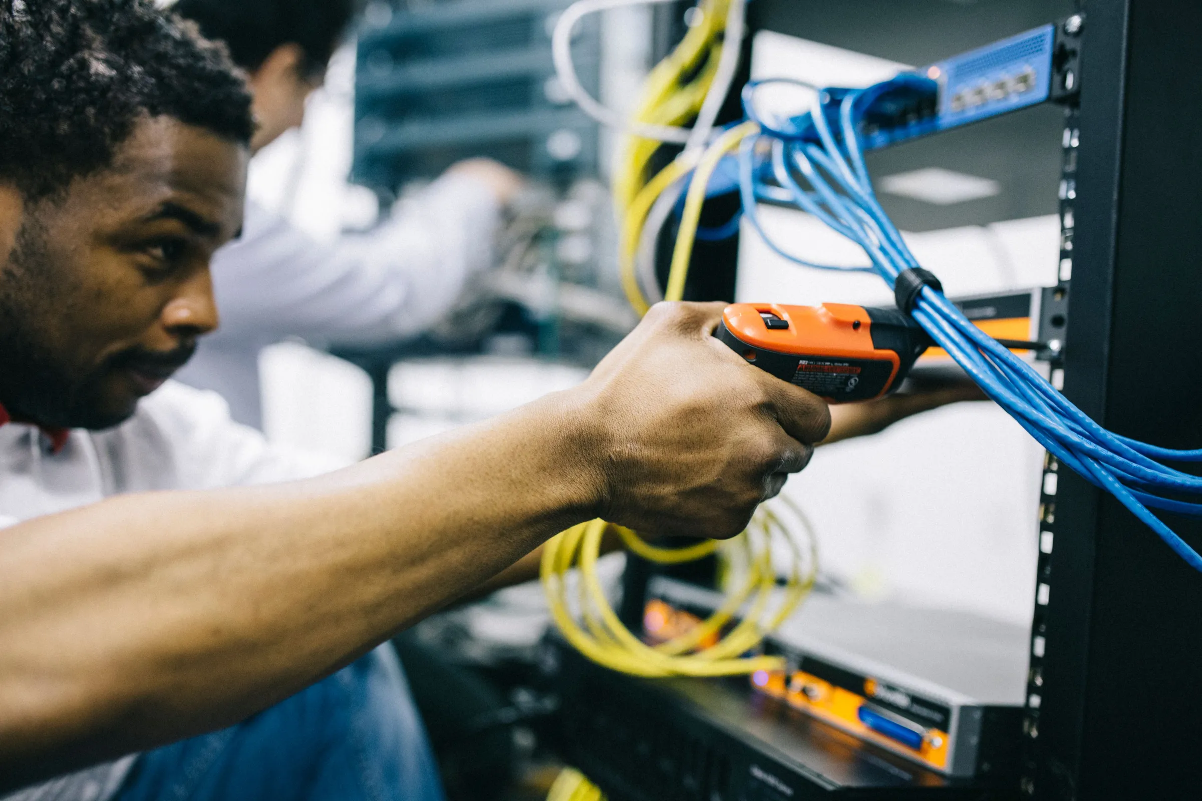 Monteur bevestigt netwerkkabels in een serverkast