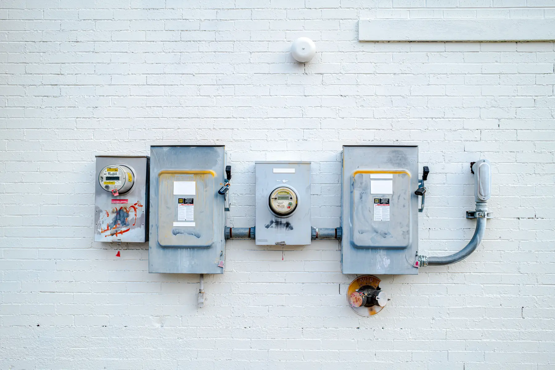 Elektriciteitsmeters en scheidingsschakelaars op een wit geverfde bakstenen muur
