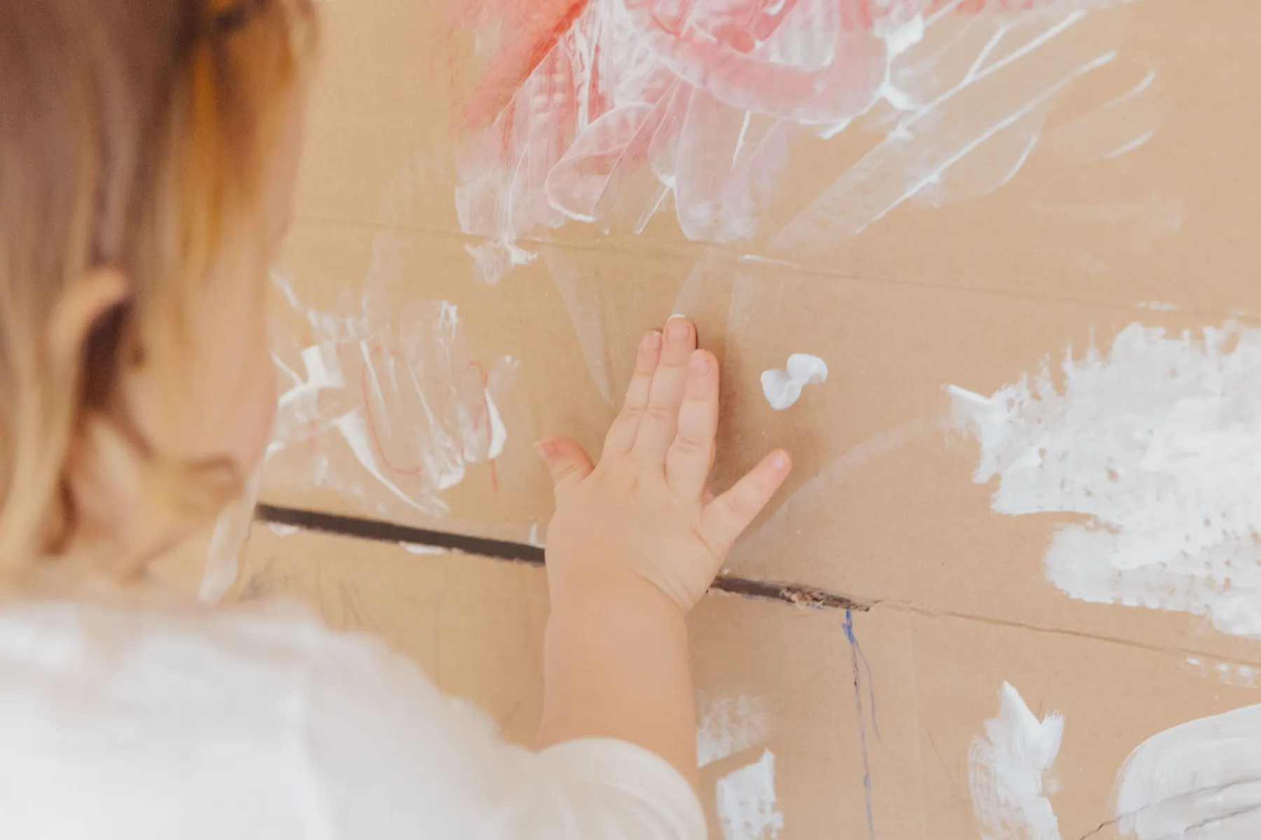 Een kinderhand schildert met witte verf