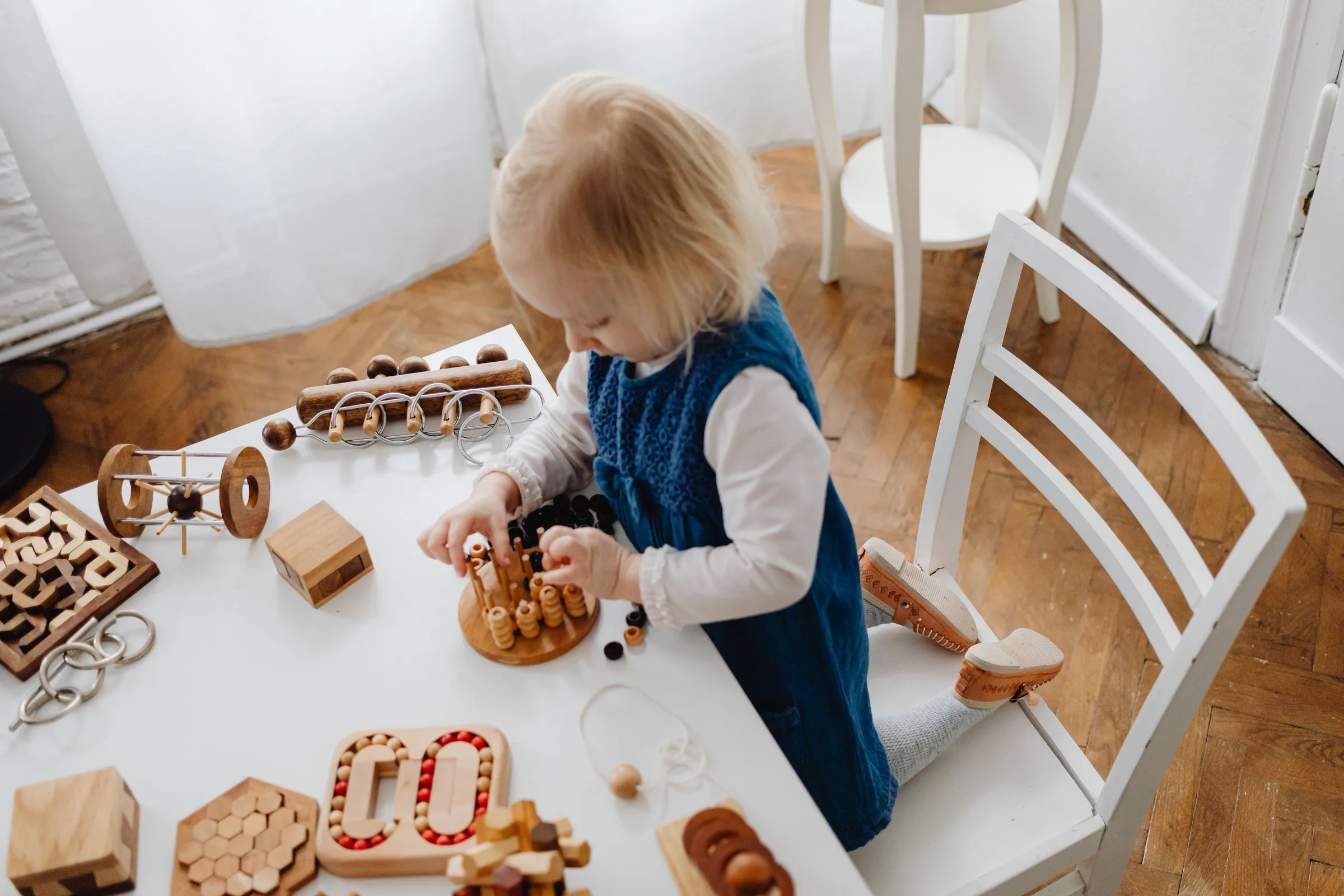 Meisje speelt met houten speelgoed aan een lage tafel
