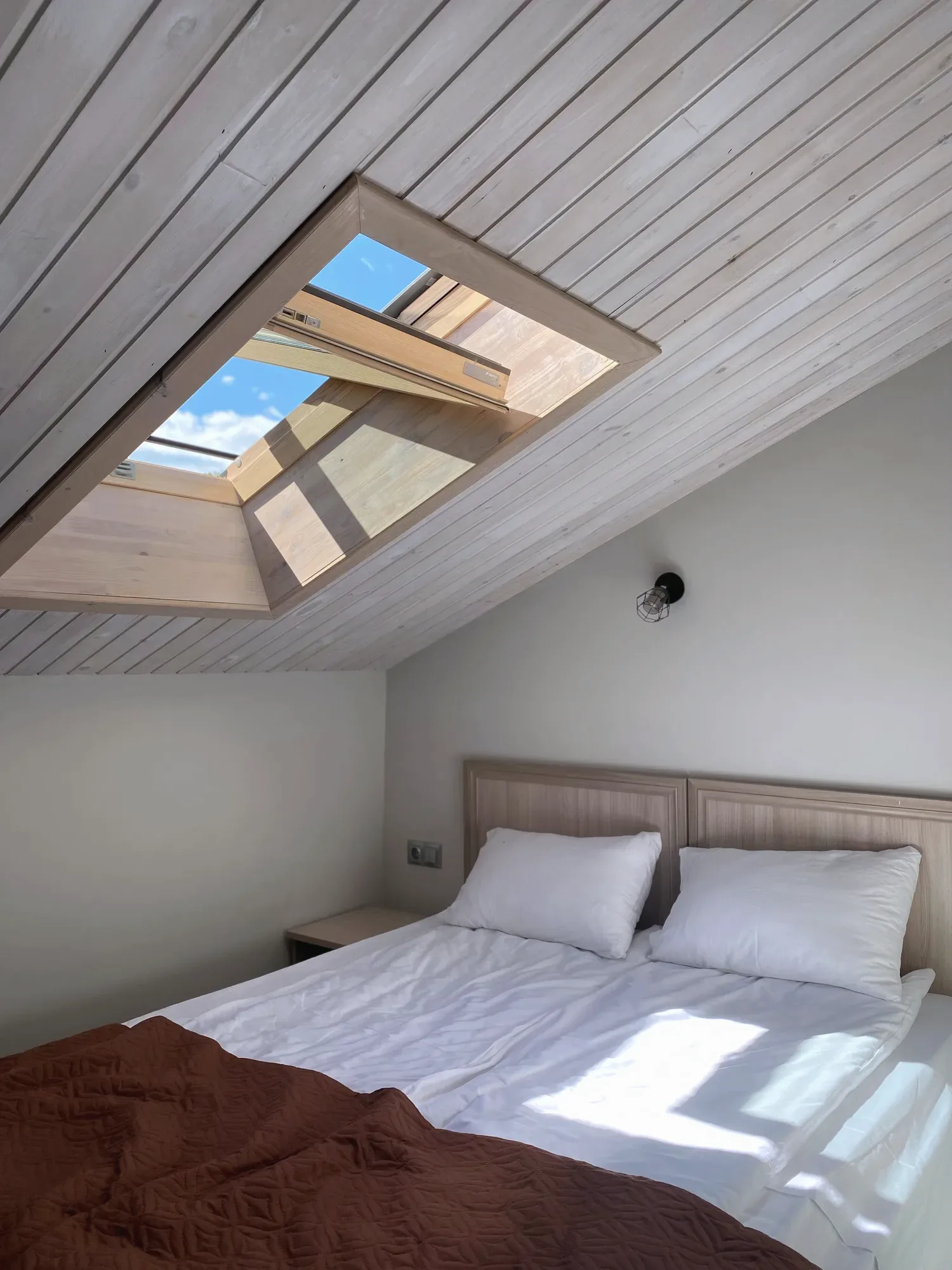 Een zolderslaapkamer met een dakraam boven het bed