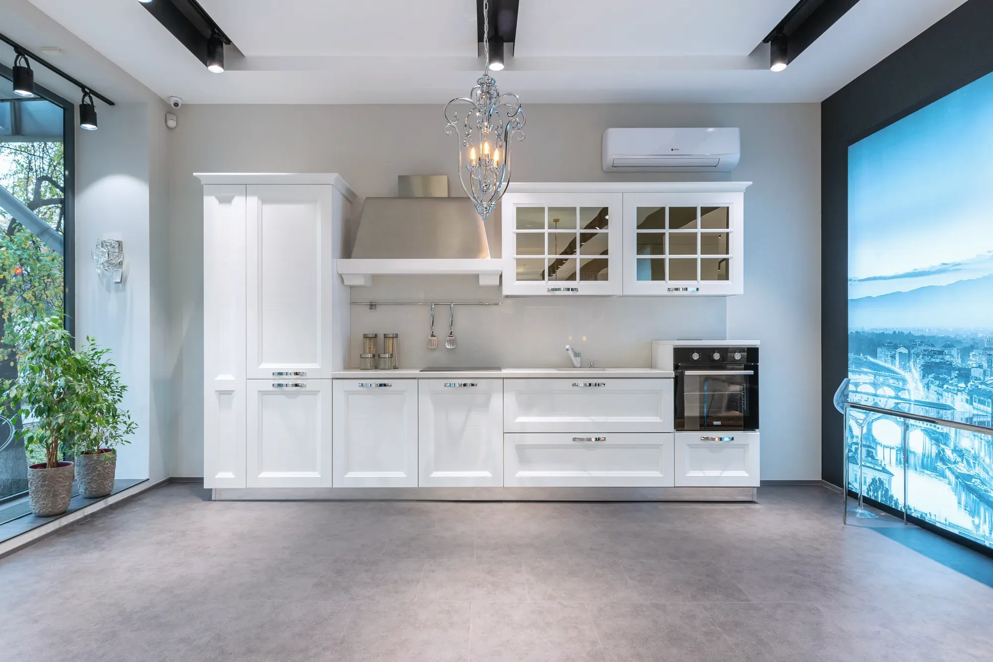 Een witte keuken met een lange werkbank en een raam met planten