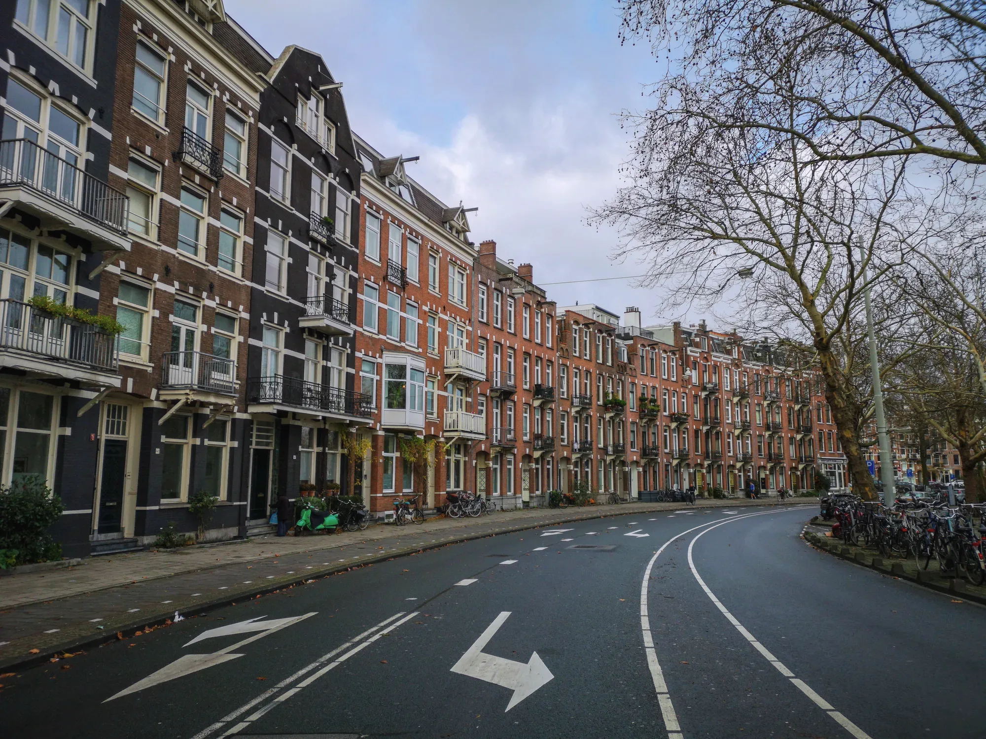 Een rij bakstenen huizen met erkers aan een brede straat